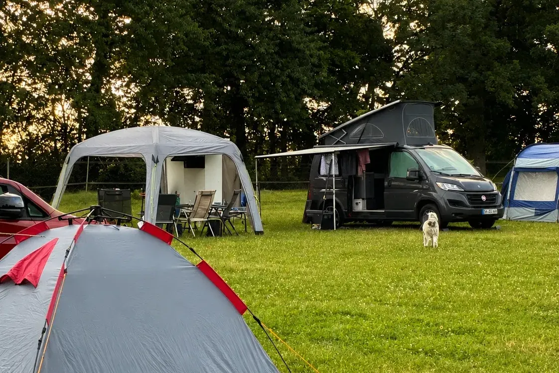 Zelt und Wohnmobil beim Campen auf der Hofwiese im Abendlicht