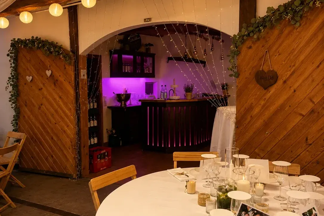 Abendlich beleuchtete Bar mit Lichterketten und gedecktem Tisch im Vordergrund