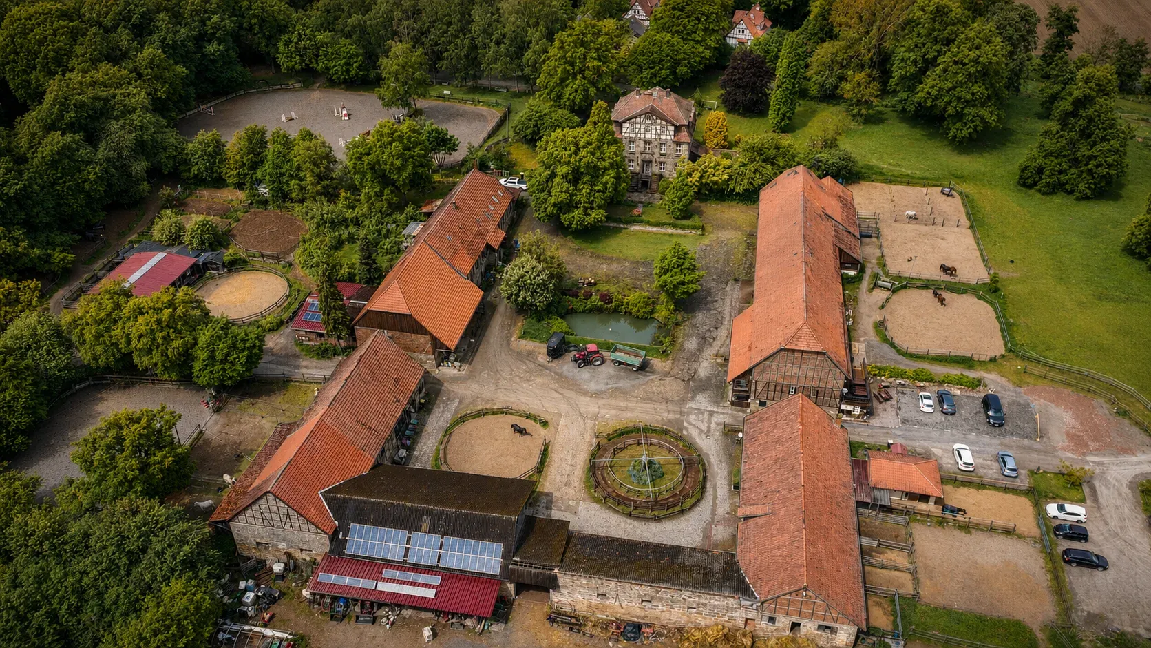 Luftaufnahme von Gut Waitzrodt bei Tag mit Gutshaus, Stallgebäuden, Reitplätzen und rundem Hofgarten